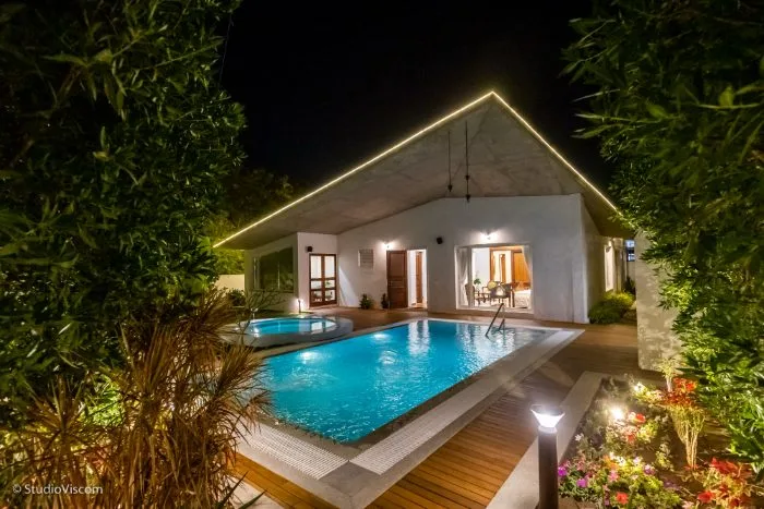 Architectural photograph of a villa and swimming pool lit at night