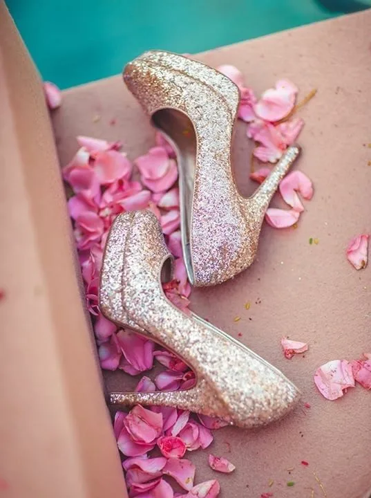 Detail of the bride's sequinned heels resting on scattered rose petals