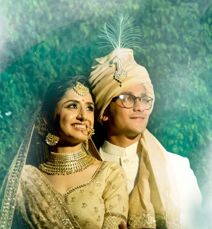 Bride and groom in ivory and gold wedding dress, photographed against a painted backdrop