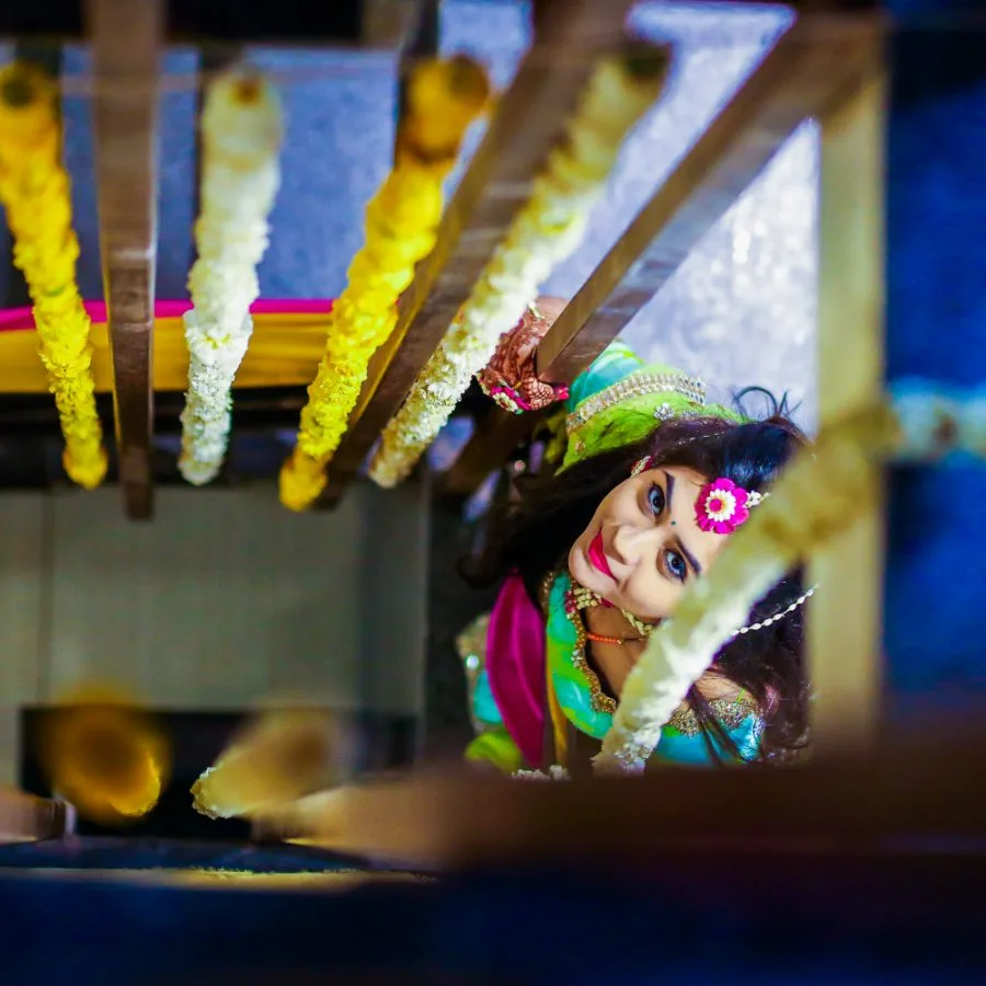 Bride seated under the mandap, framed by hanging marigold strings