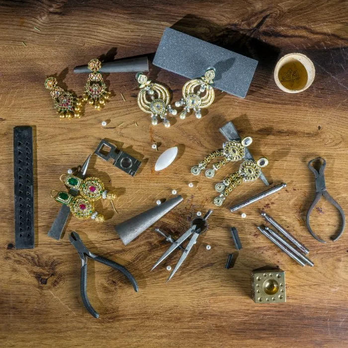 Flat-lay of jewellery pieces and a goldsmith's tools on a workbench