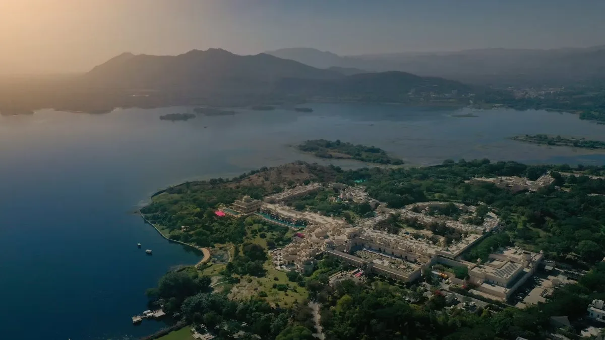 Aerial view of a lakeside destination-wedding town at dawn, hills behind it