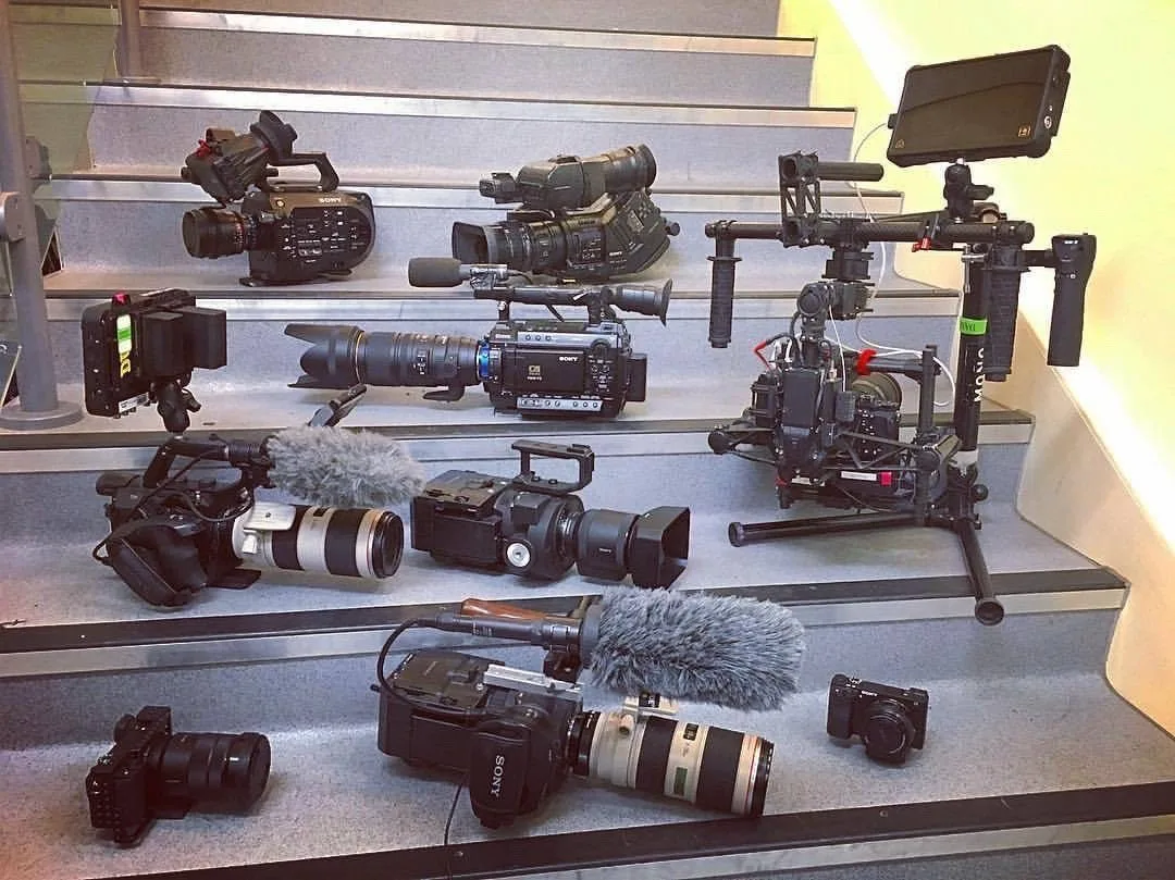Cinema camera bodies, rigs, lenses and audio gear laid out from the studio's working kit
