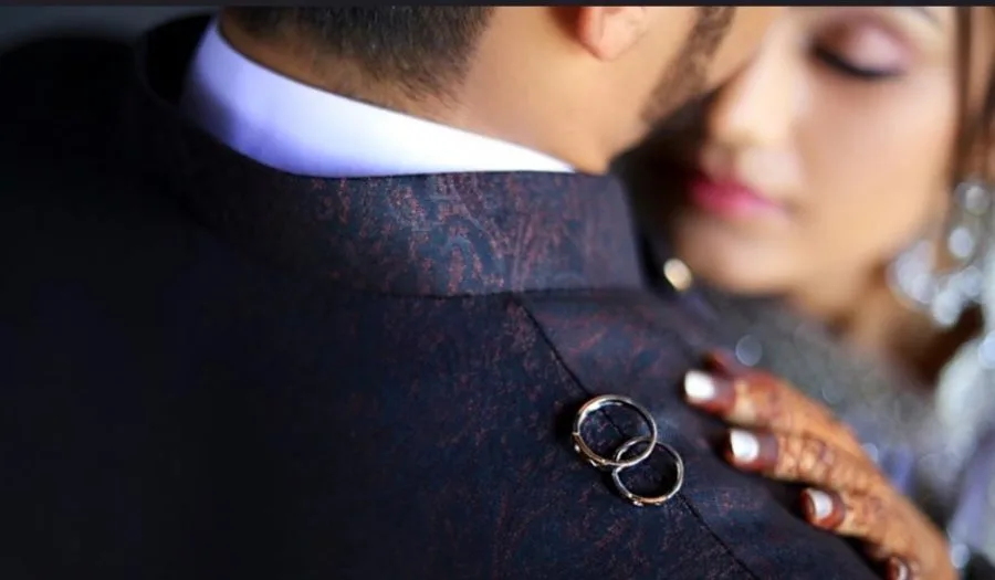 Close-up of the wedding rings held between the bride and groom