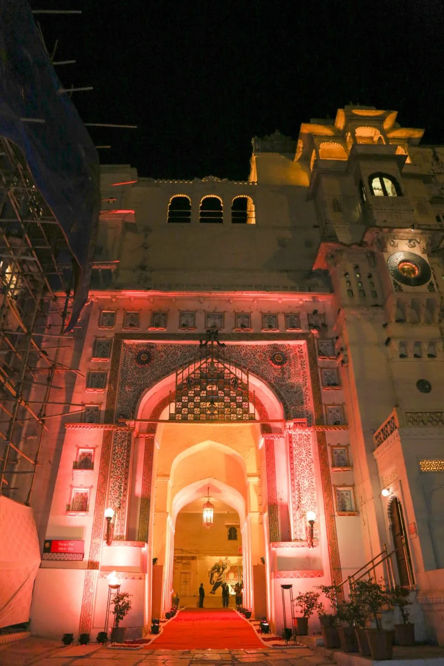 Wedding venue entrance lit in red at night, with the red carpet leading in
